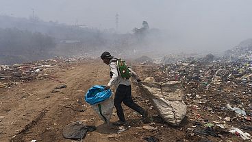 Un reciclador camina entre nubes de humo generadas por un incendio en un basurero en Villa Nueva, Guatemala, el martes 9 de abril de 2024.