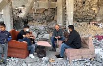 عائلة فلسطينية تجلس على أنقاض منزلها المدمر في خان يونس 