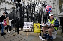 An activist sits on a toilet at the entrance to Downing Street to protest against raw sewage dumping in the rivers and seas around the UK.