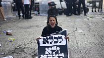 An ultra-Orthodox Jewish boy holds a sign reading in Hebrew, "To jail and not to army," during a protest on Thursday, April 11, 2024.