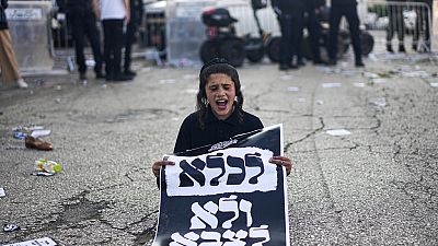An ultra-Orthodox Jewish boy holds a sign reading in Hebrew, "To jail and not to army," during a protest on Thursday, April 11, 2024.