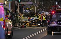 Agentes de emergencias esperan con camillas en el exterior del centro comercial Westfield, donde varias personas fueron apuñaladas en Sydney.