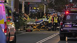Agentes de emergencias esperan con camillas en el exterior del centro comercial Westfield, donde varias personas fueron apuñaladas en Sydney.