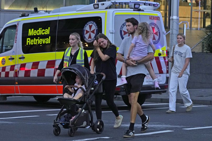 People are led out from the Westfield Shopping Centre where multiple people were stabbed in Sydney, Saturday, April 13, 2024.