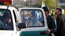 Iranian police officers detain a woman for not adhering to the strict Islamic dress code in Tehran