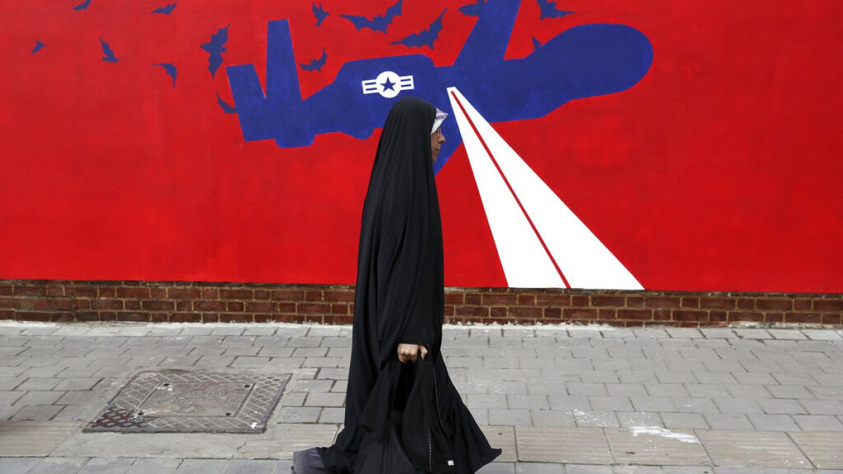 Uma mulher passa por um novo mural anti-EUA na parede da antiga embaixada dos EUA em Teerão, 2019. 
