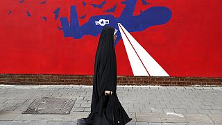 Una mujer pasa junto a un nuevo mural contra Estados Unidos en la pared de la antigua embajada estadounidense en Teherán, 2019. 