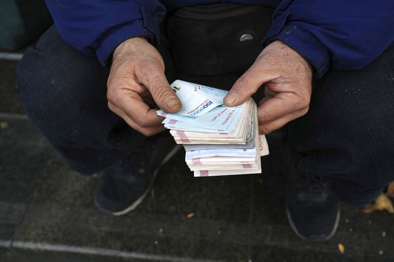 صراف في الشارع يعد الأوراق النقدية الإيرانية وسط العاصمة الإيرانية