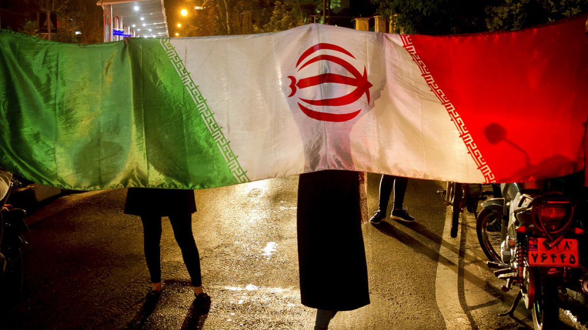 FILE - Iranians with their national flag. 