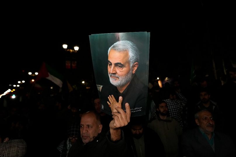 متظاهر يحمل ملصقًا لقاسم سليماني، الذي قُتل في هجوم بطائرة أمريكية بدون طيار عام 2020 في العراق.