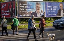 Pedoni davanti ai manifesti elettorali del Partito socialdemocratico a Zagabria, in Croazia, 14 aprile 2024