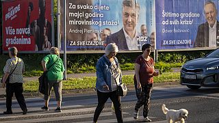 Pedoni davanti ai manifesti elettorali dell'Unione democratica croata a Zagabria, in Croazia, 14 aprile 2024