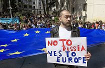 A man stands in front of protestors with a giant EU flag outside the parliament building in Tbilisi, Georgia, on Monday, April 15, 2024.