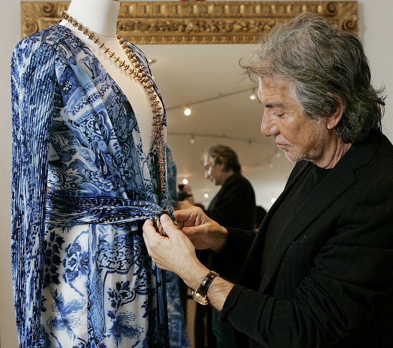 Roberto Cavalli ajusting one of his dresses on a mannequin in 2005.