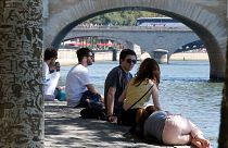 People rest by the bank of the River Seine during a heatwave in summer 2018.