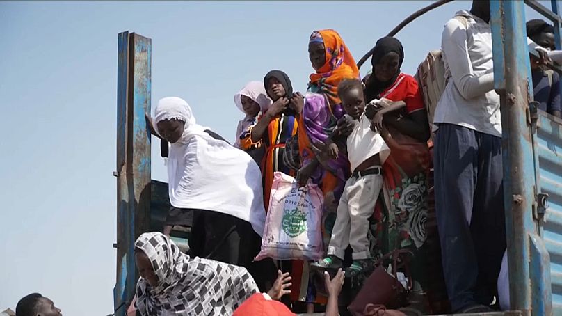 Sfollati scendono da un camion che trasporta i nuovi arrivati a un centro di transito in Sud Sudan