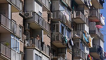 A woman hangs clothes to dry on her balcony of a housing block in Madrid, Spain, Saturday, April 13, 2024. 