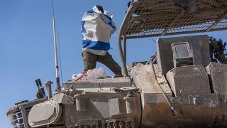 جندي إسرائيلي يحمل علم بلاده فوق ناقلة جند مدرعة بالقرب من حدود إسرائيل مع غزة، 15 أبريل/نيسان 2024