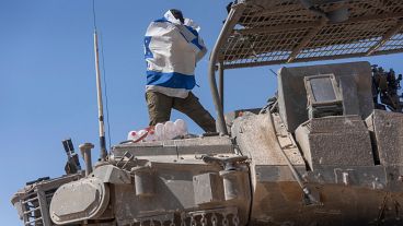 جندي إسرائيلي يحمل علم بلاده فوق ناقلة جند مدرعة بالقرب من حدود إسرائيل مع غزة، 15 أبريل/نيسان 2024