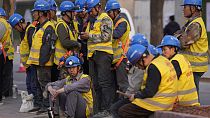 Workers wait for transport outside a construction site in Beijing, Tuesday, April 9, 2024. 