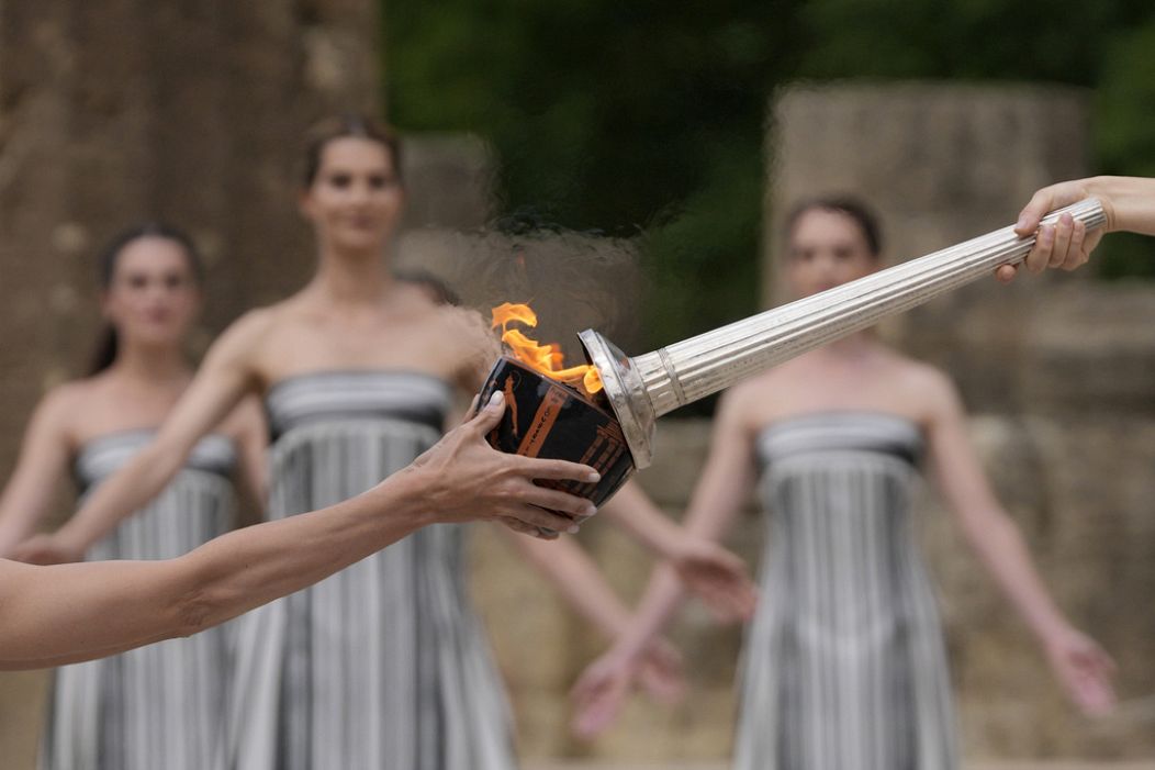 Actress Mary Mina, playing high priestess, right, lights a torch during the official ceremony of the flame lighting for the Paris Olympics.