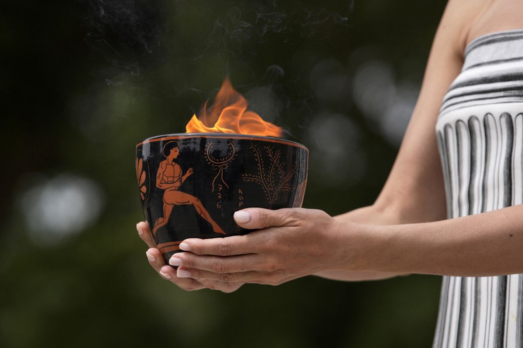 A performer holds a ceramic pot with the flame during the official ceremony.