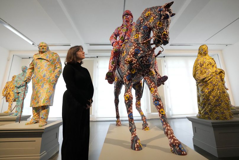 A visitor looks at sculptures made of fibreglass and handpainted by Artist Yinka Shonibare at Serpentine South in London.