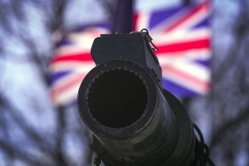 O canhão de um tanque britânico Challenger 2 contra o pano de fundo de uma bandeira do Reino Unido nas celebrações do 20º aniversário da NATO na Estónia