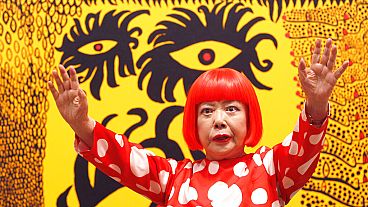 Japanese artist Yayoi Kusama poses for photographers at the 'Earth Carrying with it a Tale of the Cosmos' at the Tate Modern in London, 2012. 