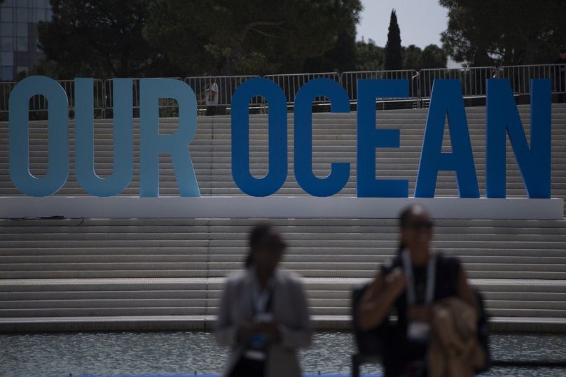 People walk in front of an 'Our Ocean' sign during the 'Our Ocean Conference' at the Stavros Niarchos Foundation Cultural Centre.