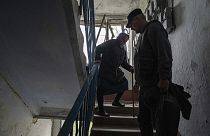 Um voluntário ajuda Olga, 79 anos, a descer as escadas do seu apartamento, que foi fortemente danificado por um ataque aéreo russo
