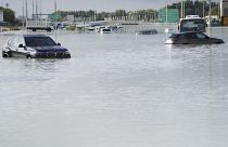 Vehicles sit abandoned in floodwater covering a major road in Dubai, United Arab Emirates
