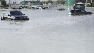 In Dubai ließen Menschen in Autos  ihre überschwemmten Fahrzeuge zurück und gingen zu Fuß weiter.