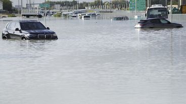 Vehicles sit abandoned in floodwater covering a major road in Dubai, United Arab Emirates