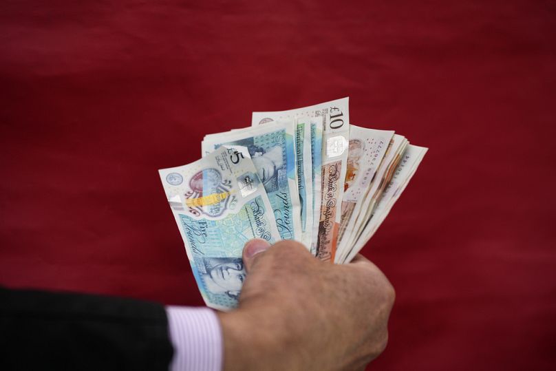 A bookmaker holds British pounds bills on Ladies Day, the second day of the Grand National Horse Racing meeting, at Aintree racecourse, near Liverpool, April 2024