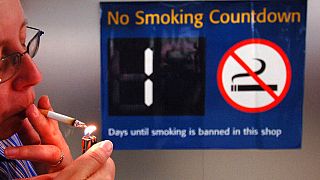 Sigara yasağı için geri sayımın başladığını bildiren  tabela önünde sigara yakan bir kişi