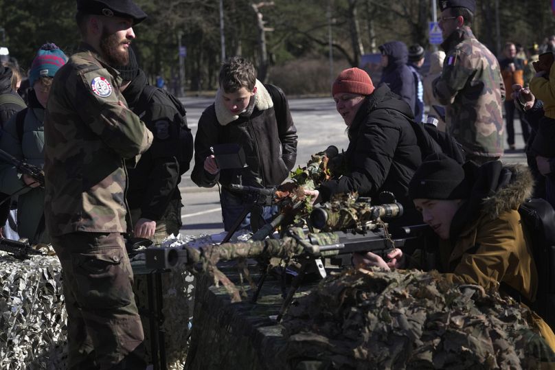 La gente ve una variedad de rifles en exhibición durante una celebración por el 20 aniversario de la adhesión de Estonia a la OTAN, en Tallin, Estonia, 04/04/2024