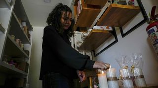 Una mujer enciende velas en su tienda después de un corte de energía programado ordenado por el Ministerio de Energía, en Quito, Ecuador, el martes 16 de abril de 2024.