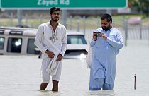 Two men walk through floodwater in Dubai.