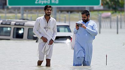 Two men walk through floodwater in Dubai.