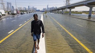 Un hombre camina a lo largo de una barrera entre las inundaciones causadas por las fuertes lluvias en Dubái, Emiratos Árabes Unidos, el 18 de abril de 2024.