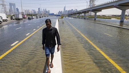 Un hombre camina a lo largo de una barrera entre las inundaciones causadas por las fuertes lluvias en Dubái, Emiratos Árabes Unidos, el 18 de abril de 2024.