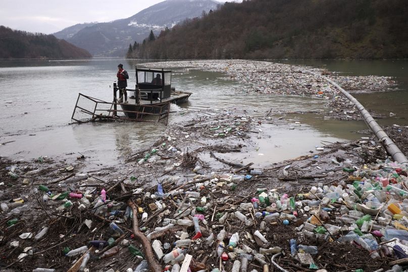Utility company workers push the waste to the shore of Lim river near Priboj, January 2023