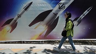 Eine Frau geht im Norden Teherans an einem Banner vorbei, auf dem Raketenabschüsse zu sehen sind