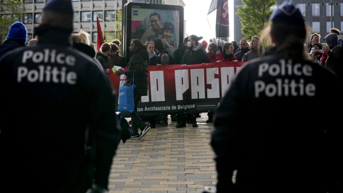 La polizia guarda i manifestanti che tengono uno striscione fuori dalla conferenza del Conservatorismo nazionale a Bruxelles