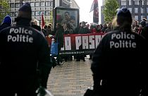 La polizia guarda i manifestanti che tengono uno striscione fuori dalla conferenza del Conservatorismo nazionale a Bruxelles
