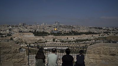 La gente visita el Monte de los Olivos con vistas a la Cúpula de la Roca en el recinto de la Mezquita de Al Aqsa en la Ciudad Vieja de Jerusalén, el 19 de abril de 2024.