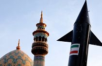 نموذج لصاروخ يحمله متظاهرون إيرانيون، بينما تظهر مئذنة وقبة مسجد في الخلفية خلال تجمع مناهض لإسرائيل في ساحة فلسطين في طهران، إيران، الاثنين 15 أبريل 2024.