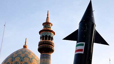 نموذج لصاروخ يحمله متظاهرون إيرانيون، بينما تظهر مئذنة وقبة مسجد في الخلفية خلال تجمع مناهض لإسرائيل في ساحة فلسطين في طهران، إيران، الاثنين 15 أبريل 2024.