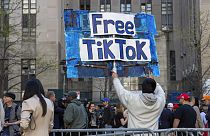 Um homem carrega um cartaz "Free TikTok" em frente ao tribunal onde teve início o julgamento de Donald Trump por suborno, a 15 de abril de 2024, em Nova Iorque.